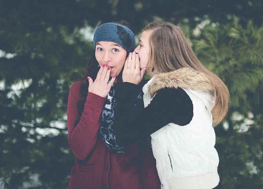 A photo of a woman whispering to another woman